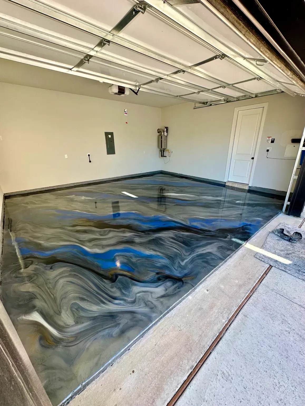 Garage with epoxy flooring in shades of blue, gray, and black.