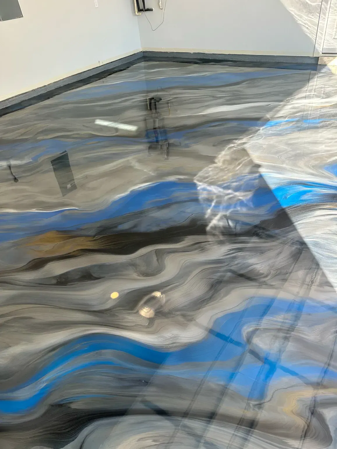 Metallic epoxy floor with blue, gray, and silver swirls.