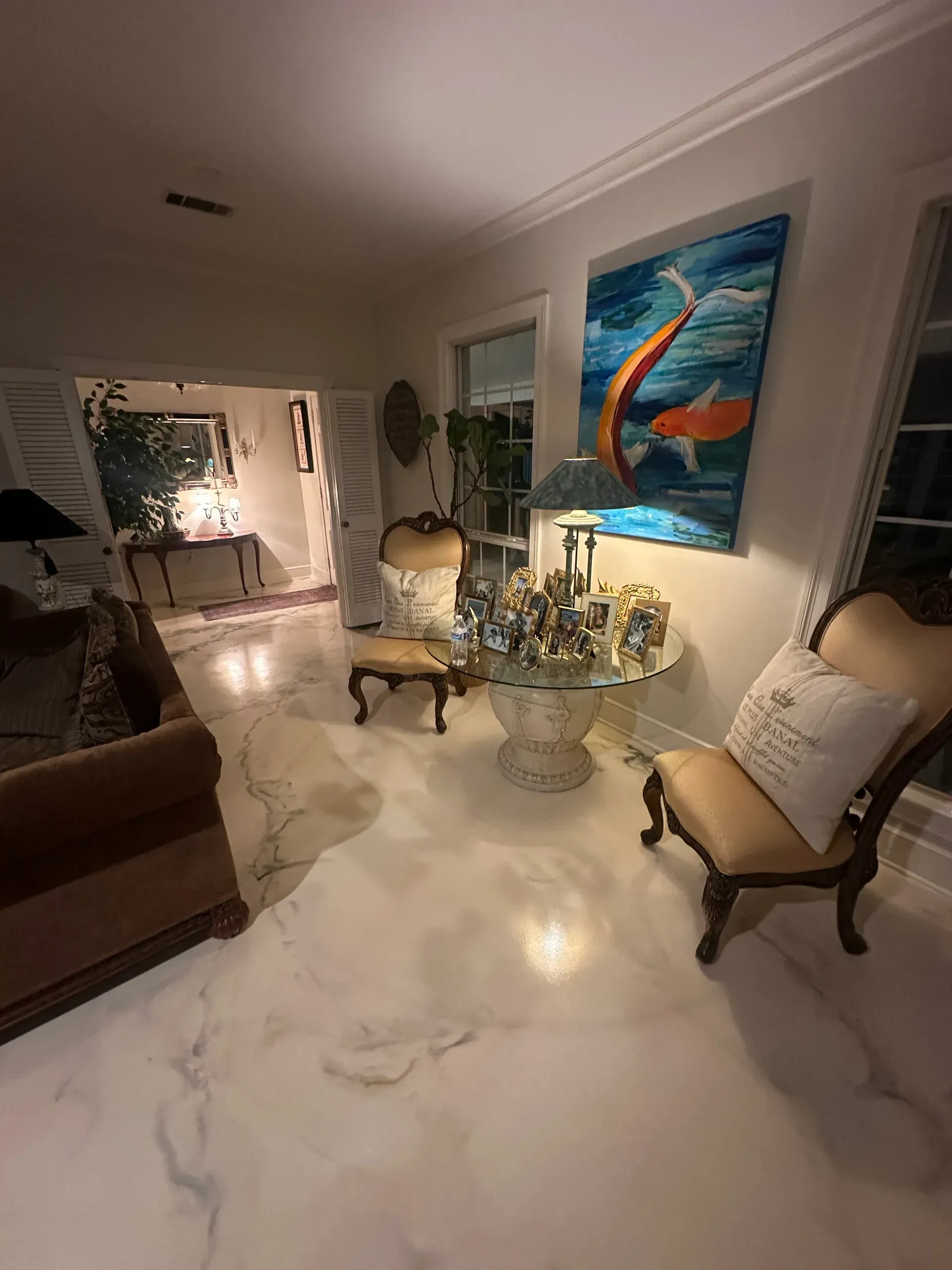 Living room with white marble floors, koi fish painting, ornate furniture, and open doorway.