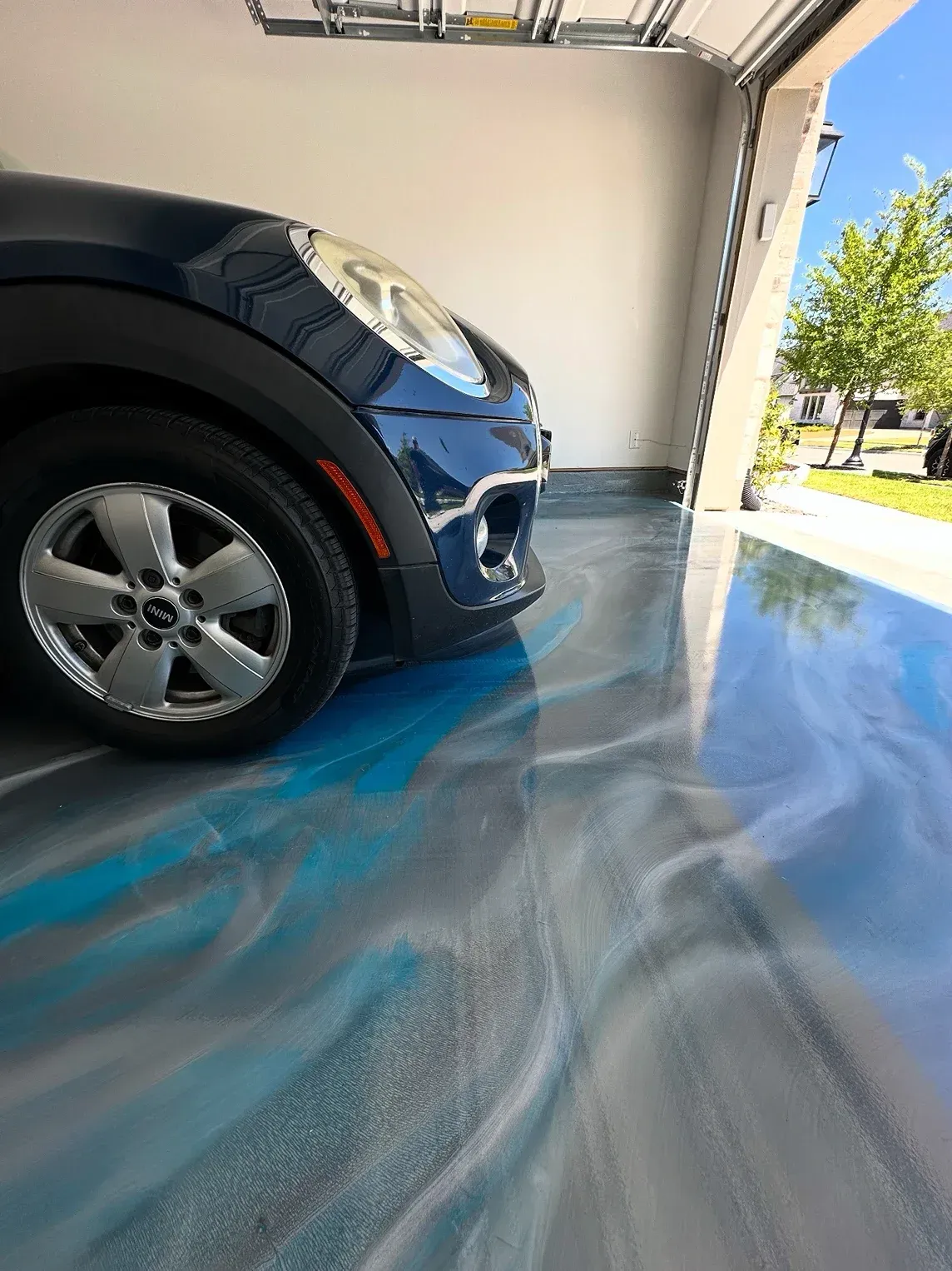 Blue and silver epoxy garage floor with a dark blue Mini Cooper partially visible in the garage.
