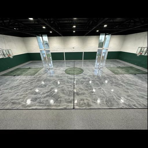 Indoor basketball court with shiny gray floor and green walls. Two glass structures rise from the floor.