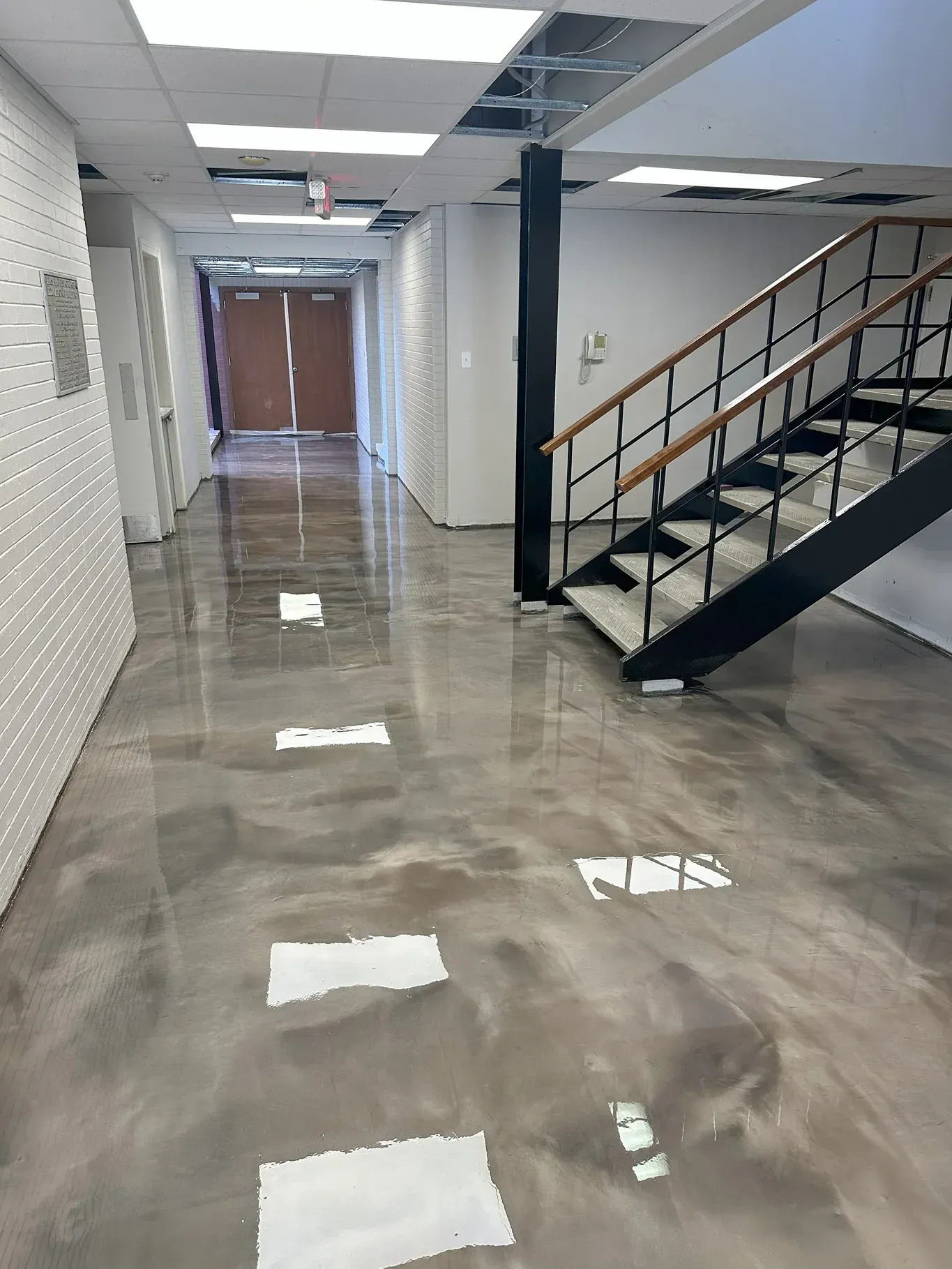 Hallway with metallic epoxy floor, stairs, and textured white wall on the left.