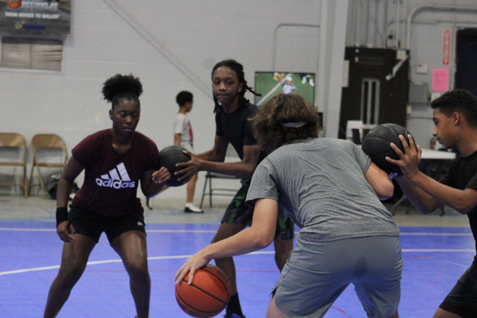 Four individuals practicing basketball drills on a blue court inside an indoor facility.