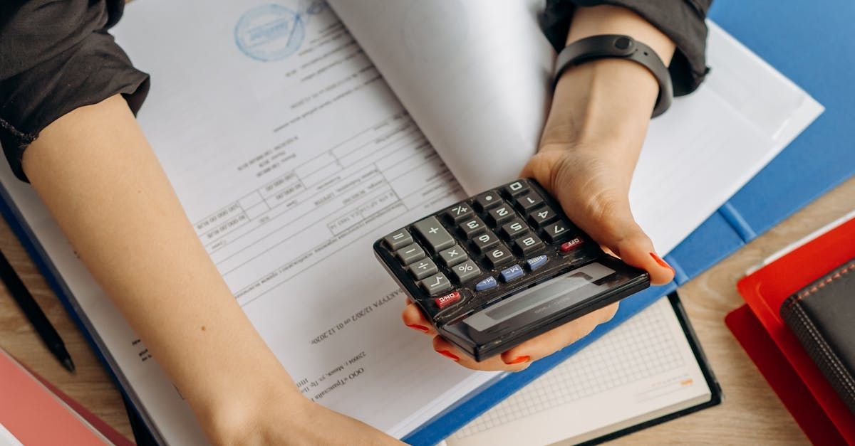 A person holding a calculator in front of a book.