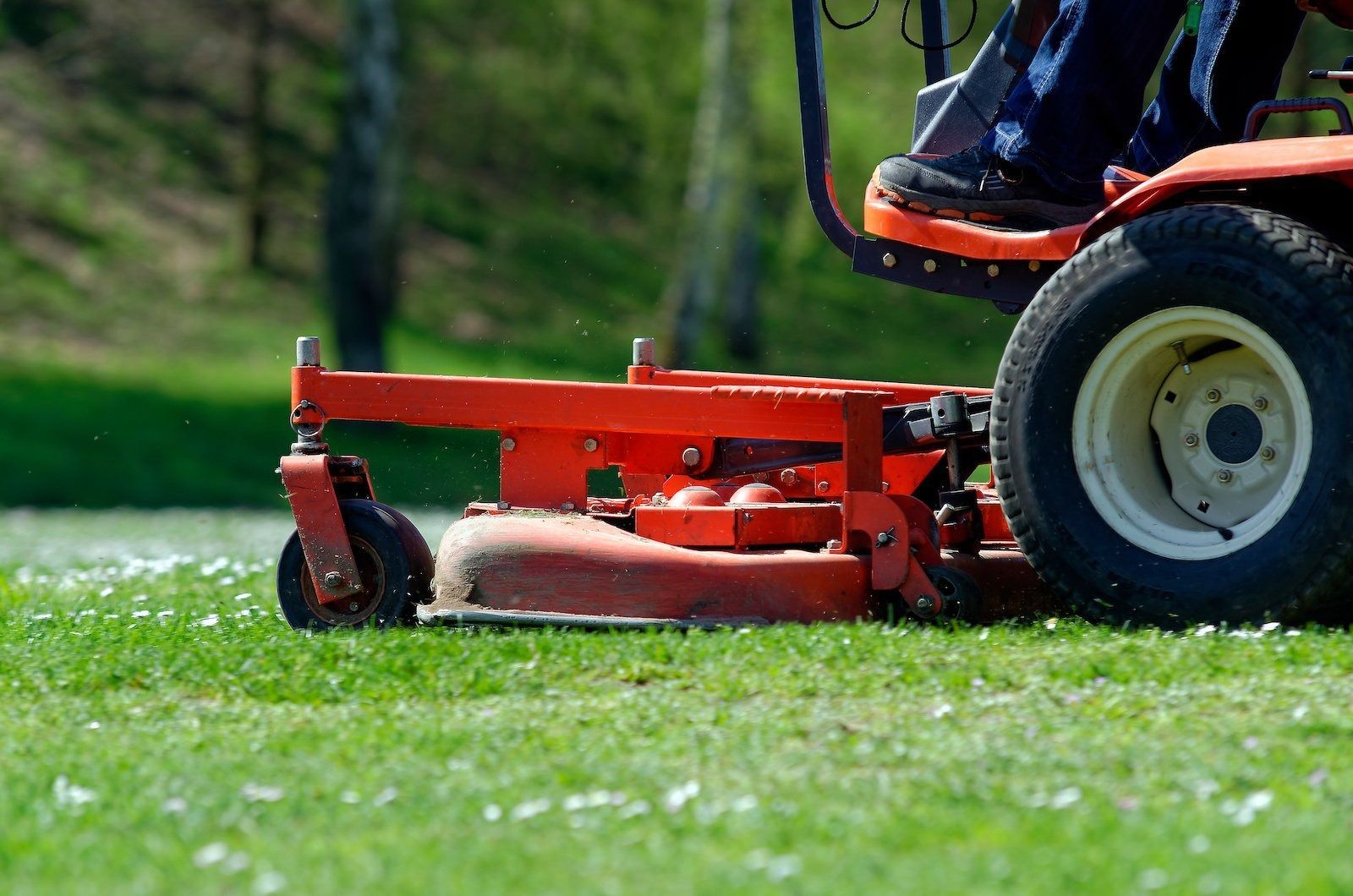 A person is riding a lawn mower on a lush green field.