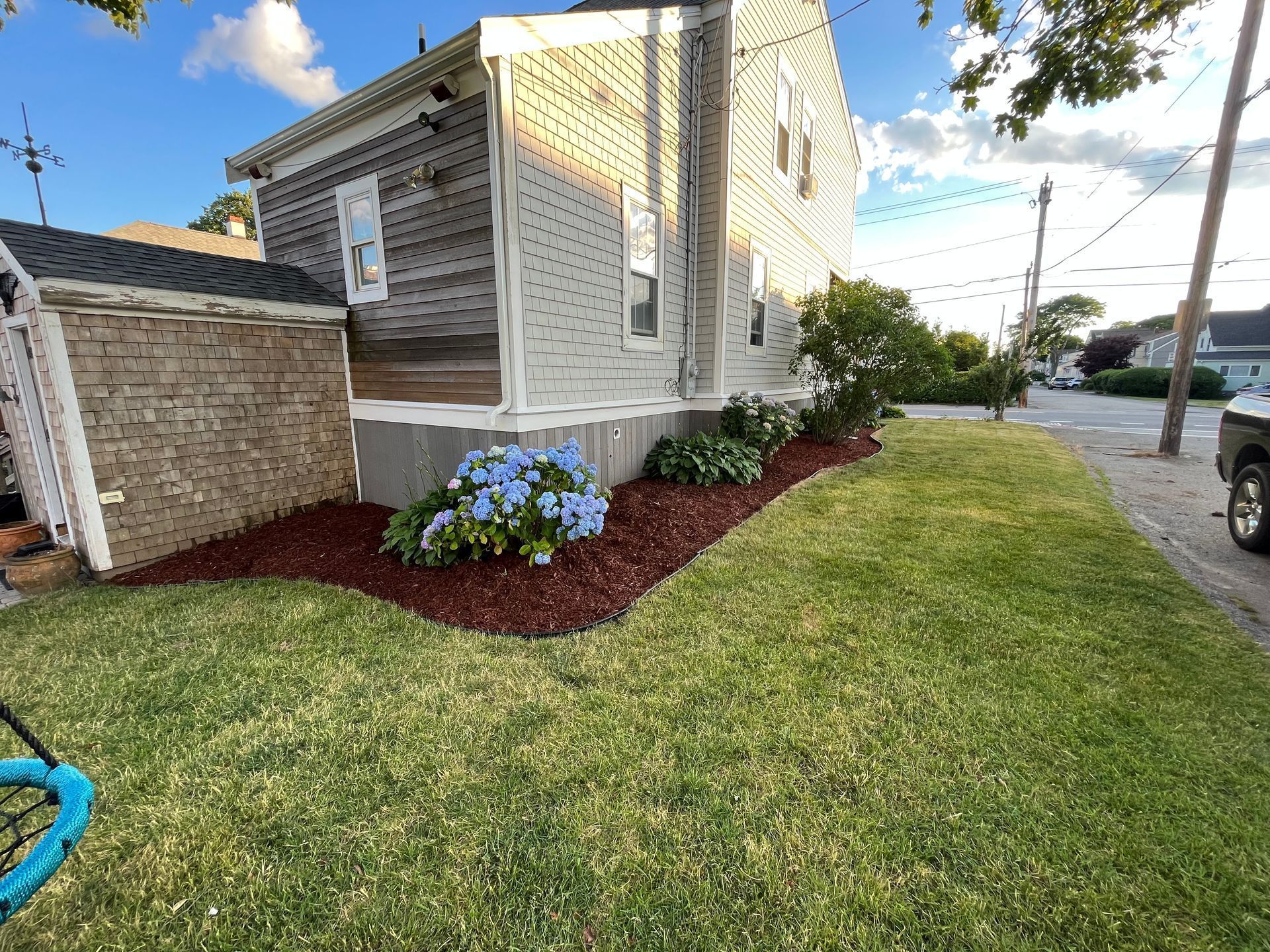 A lawn with flowers and mulch in front of a house.