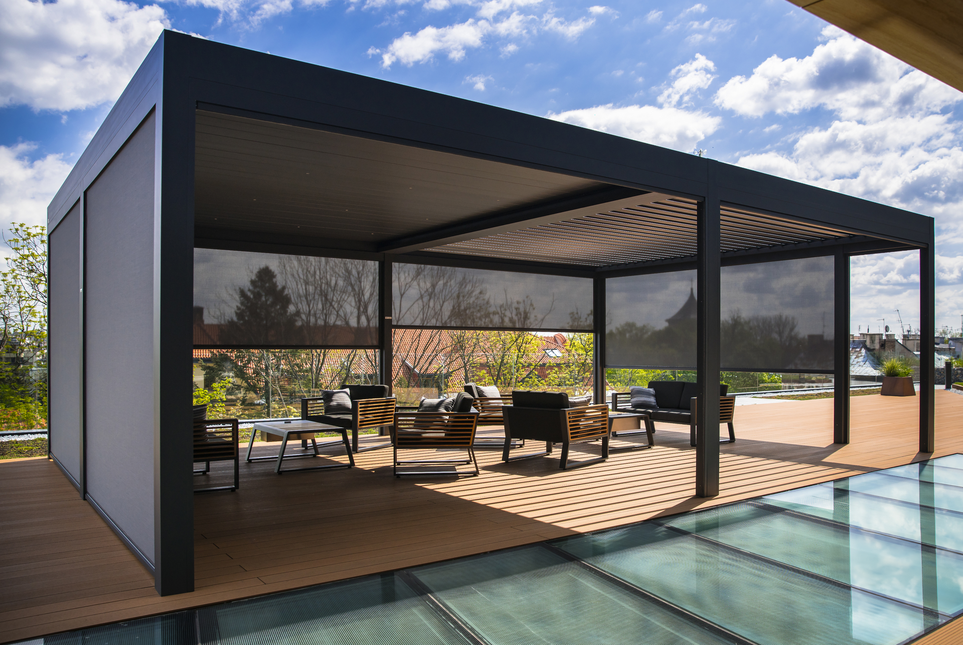 C'è un pergolato bioclimatio con molti mobili sotto.