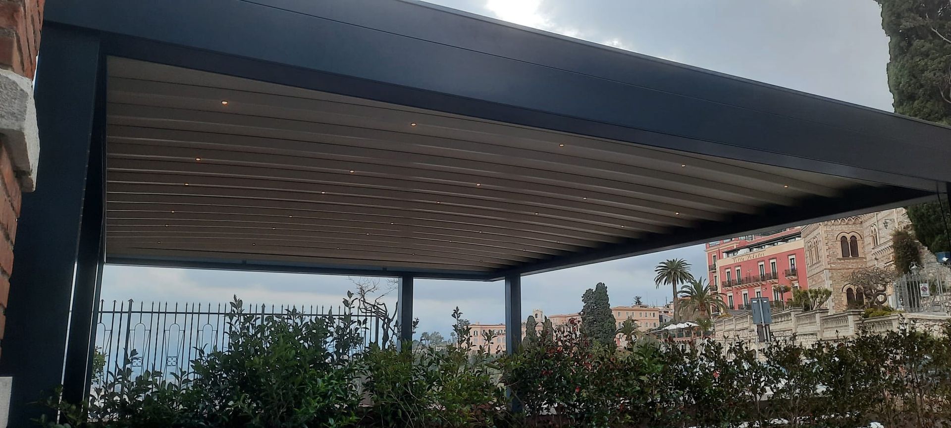 Un pergolato è situato in cima a un edificio in mattoni accanto a una recinzione.