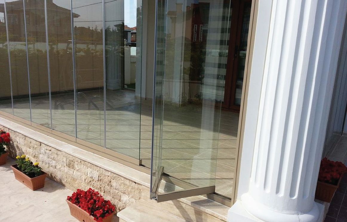 Un pilastro bianco è accanto a una porta a vetri con dei fiori davanti.