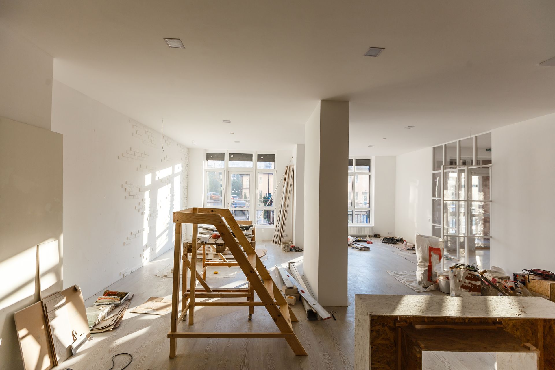 A large room with a wooden ladder in the middle of it is being remodeled.