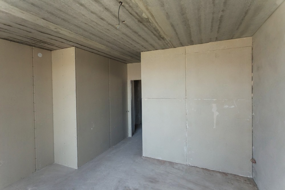 An empty room with white walls and a concrete ceiling.