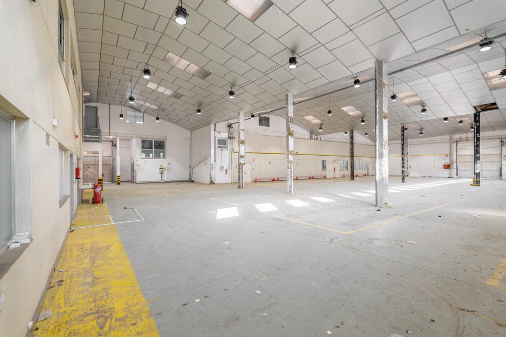 A large empty warehouse with a yellow stripe on the floor