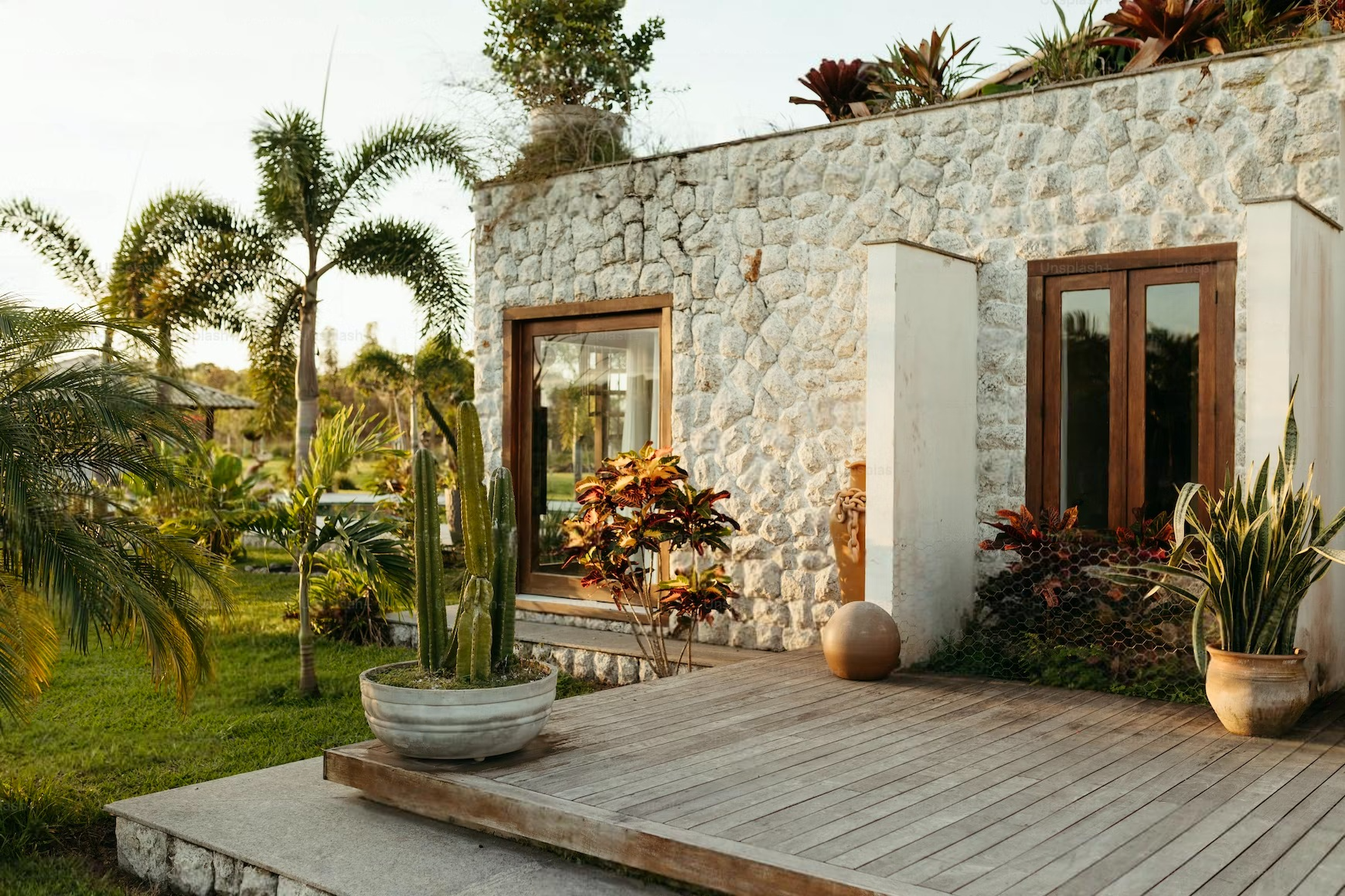 A white stone house with a wooden deck in front of it.