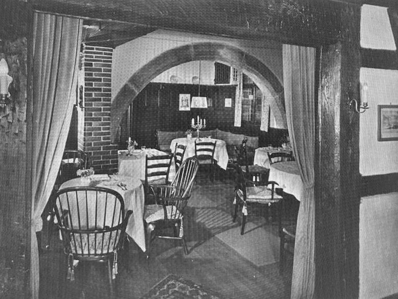 Ein Schwarzweißfoto eines Restaurants mit Tischen und Stühlen