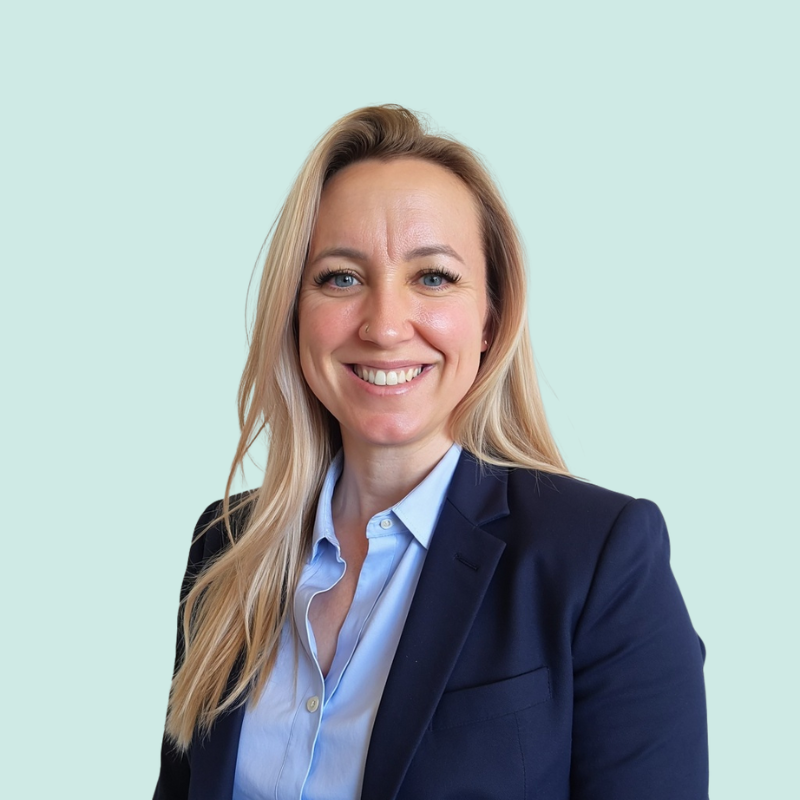 Woman with blonde hair wearing a blue button-down shirt and navy blazer, smiling at the camera.
