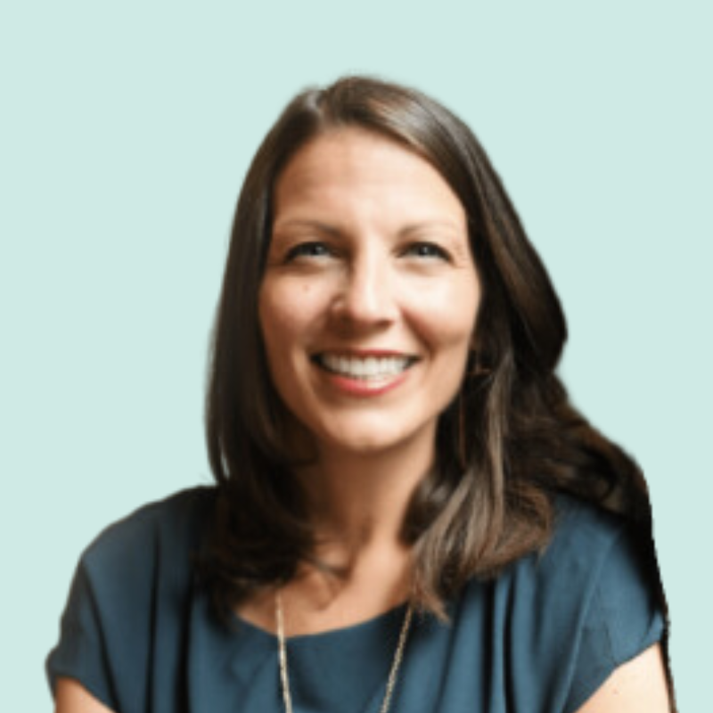 Woman smiling, dark hair, blue top, light blue background.