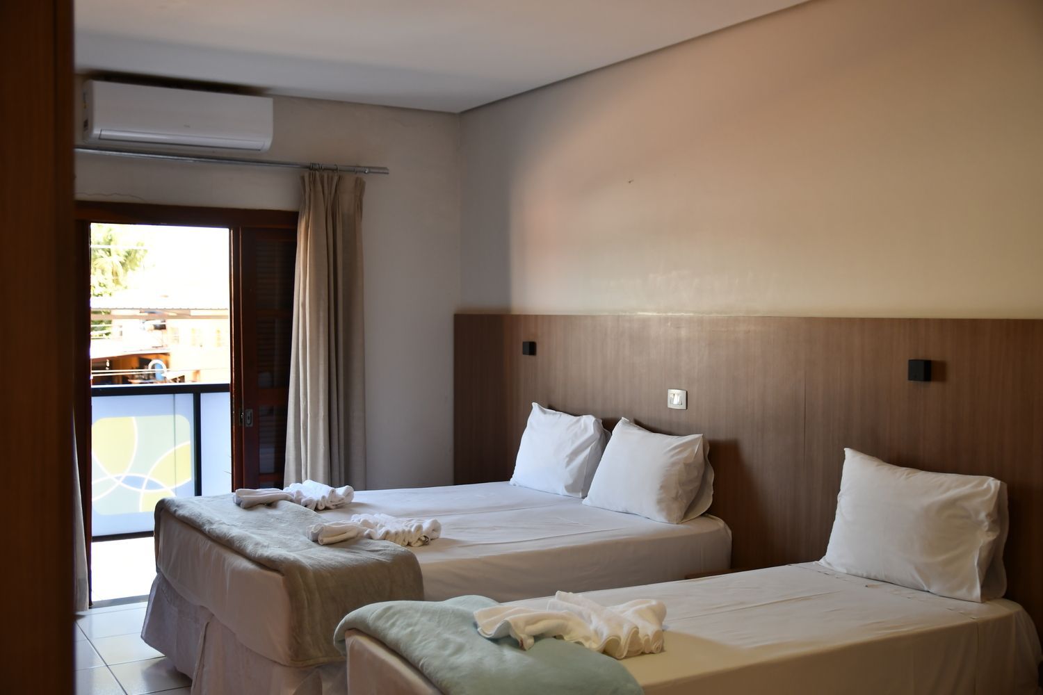 Um quarto de hotel com três camas e uma varanda.