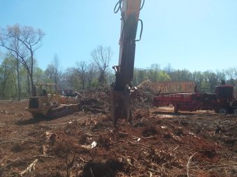A large excavator is in the middle of a dirt field