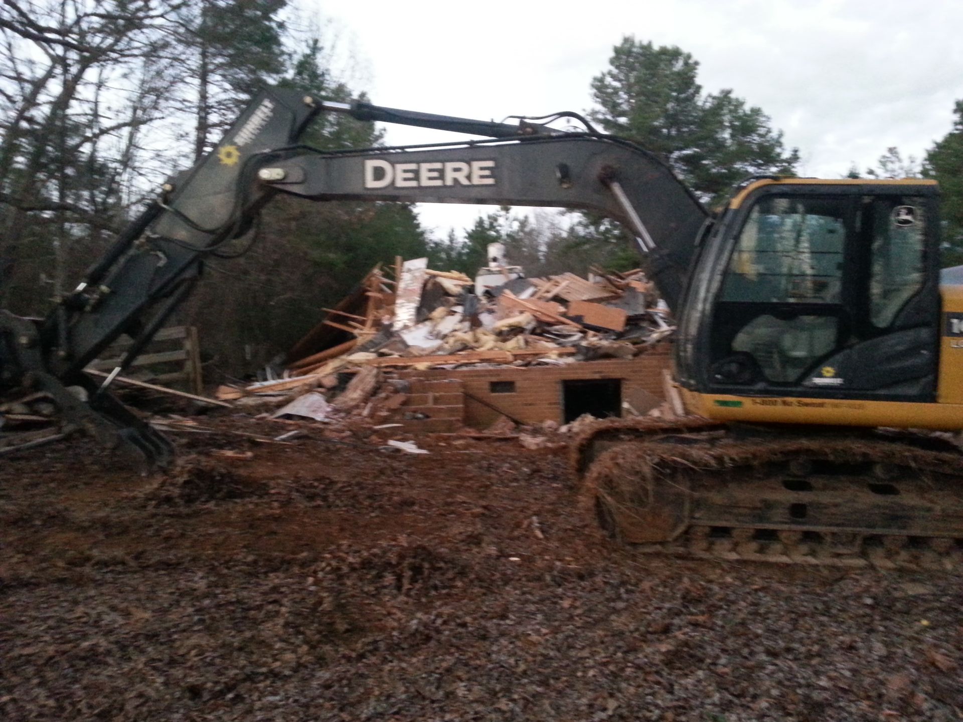 A deere excavator is demolishing a house in the woods