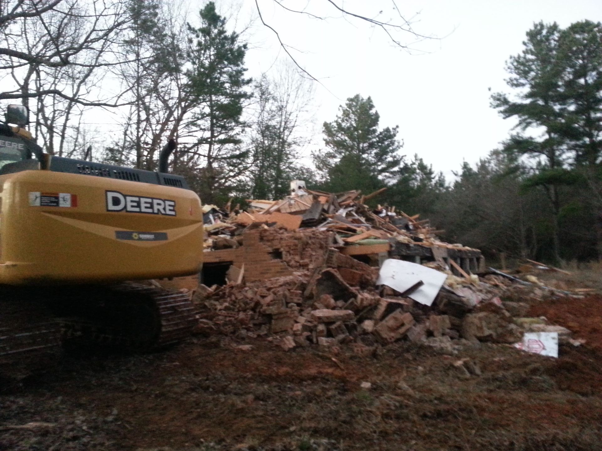 A deere excavator is working on a pile of rubble.