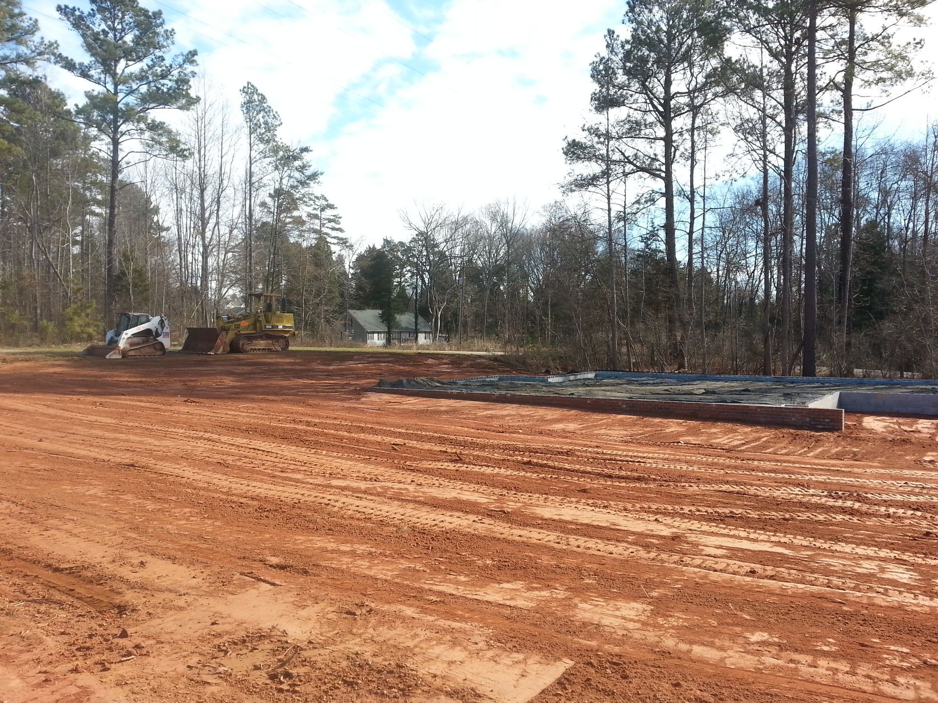 A bulldozer is moving dirt in a field with trees in the background.
