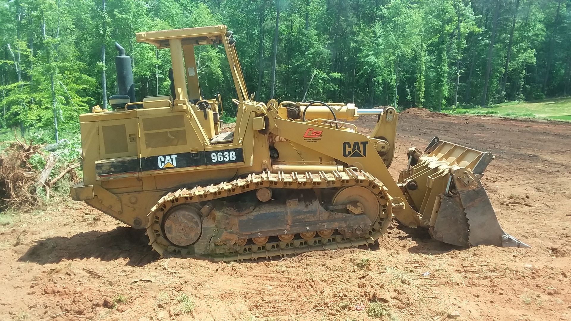 A yellow cat bulldozer is parked in a dirt field