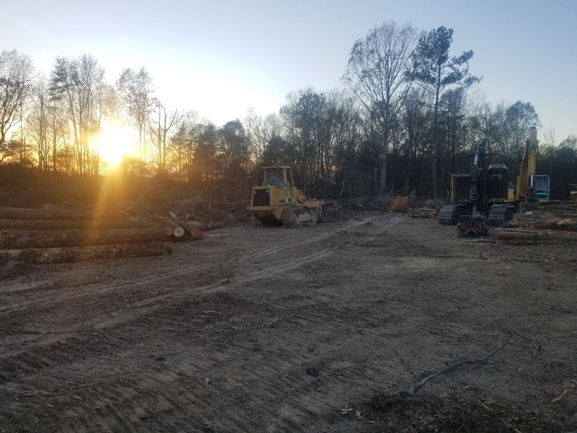 A construction site with a lot of machinery and trees in the background.