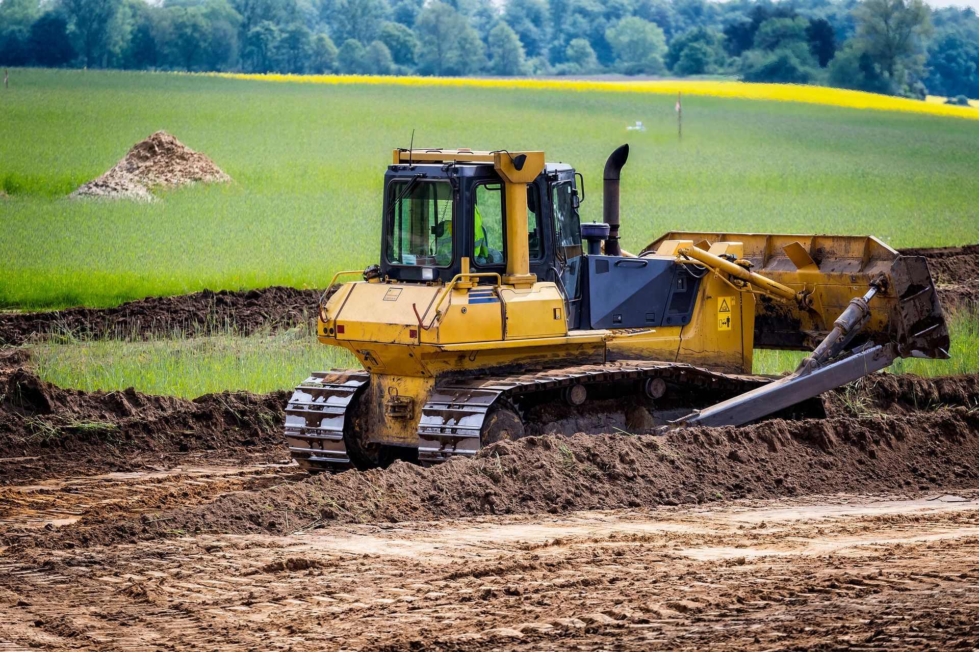 A bulldozer is driving through a dirt field.