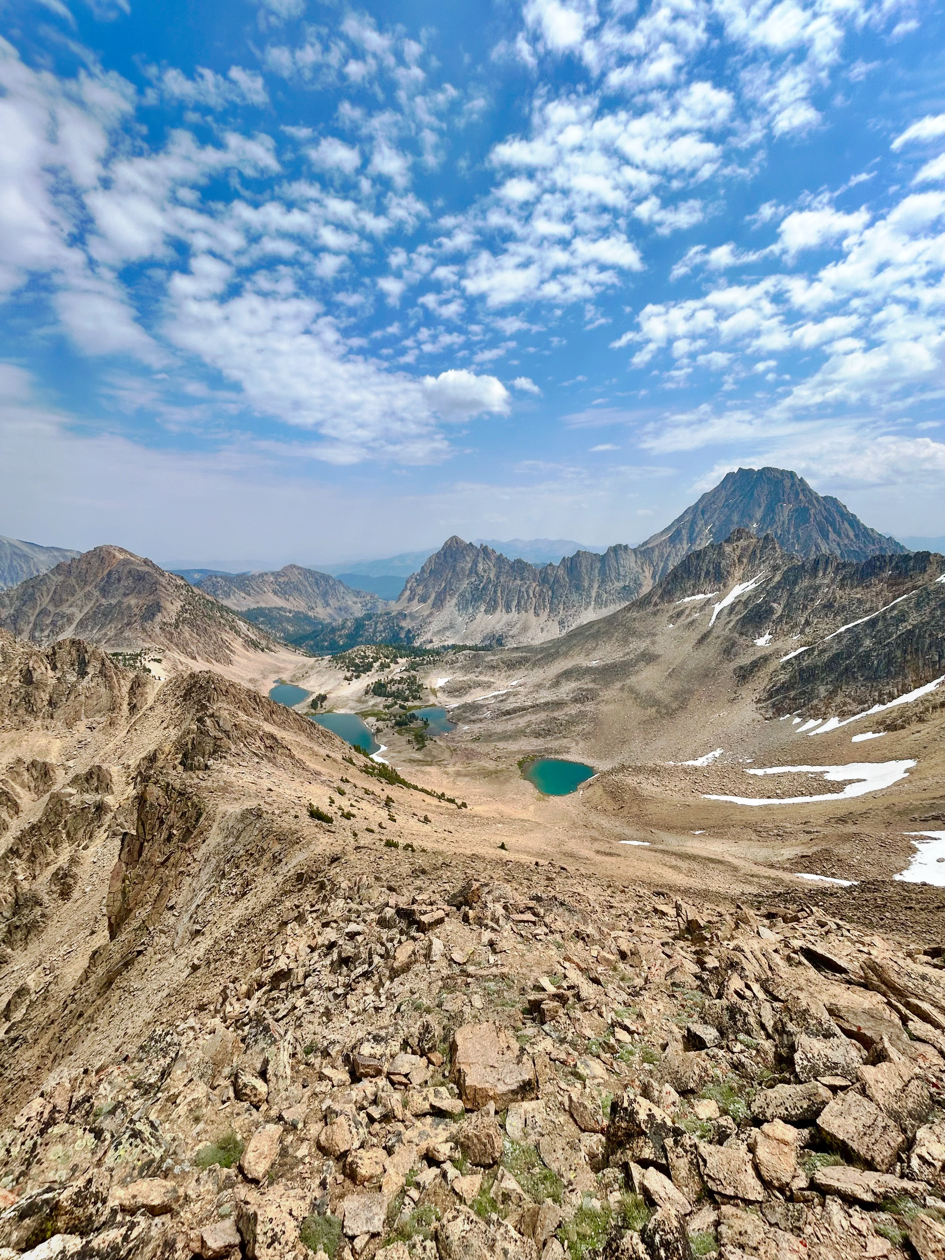 Rugged mountain vista with turquoise lakes under a cloudy blue sky.