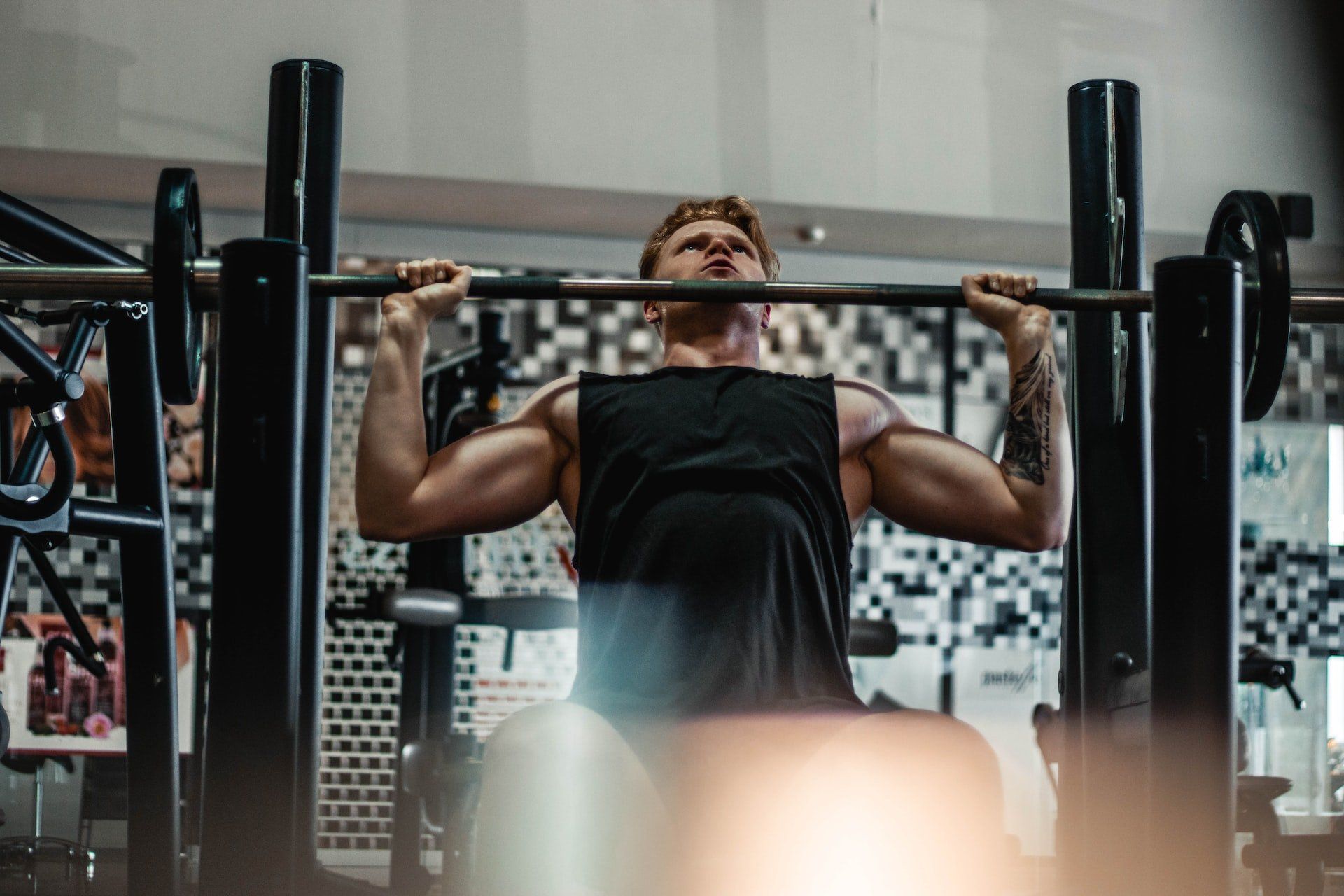 A man is doing pull ups on a bar in a gym.