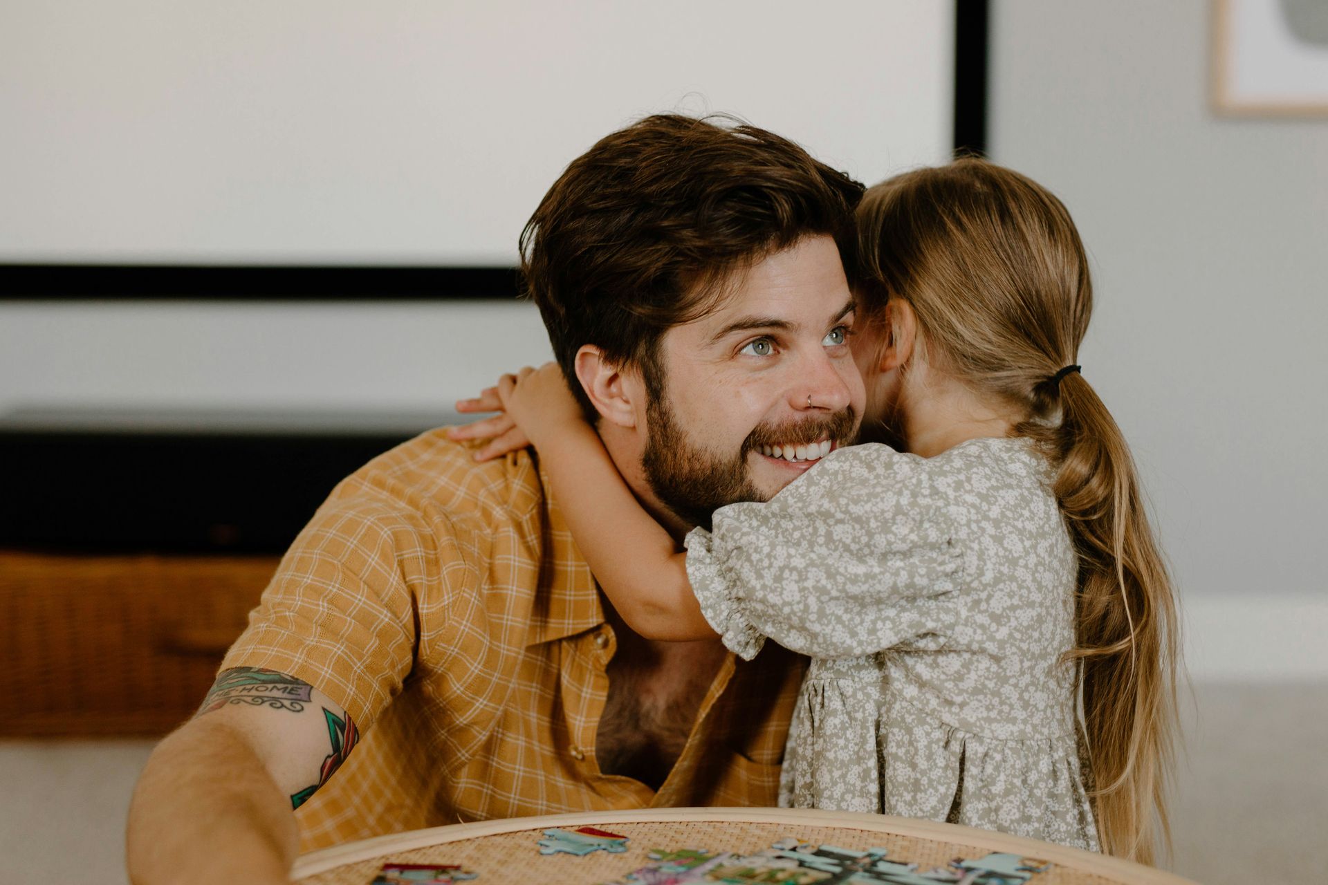 A little girl is whispering into a man 's ear.