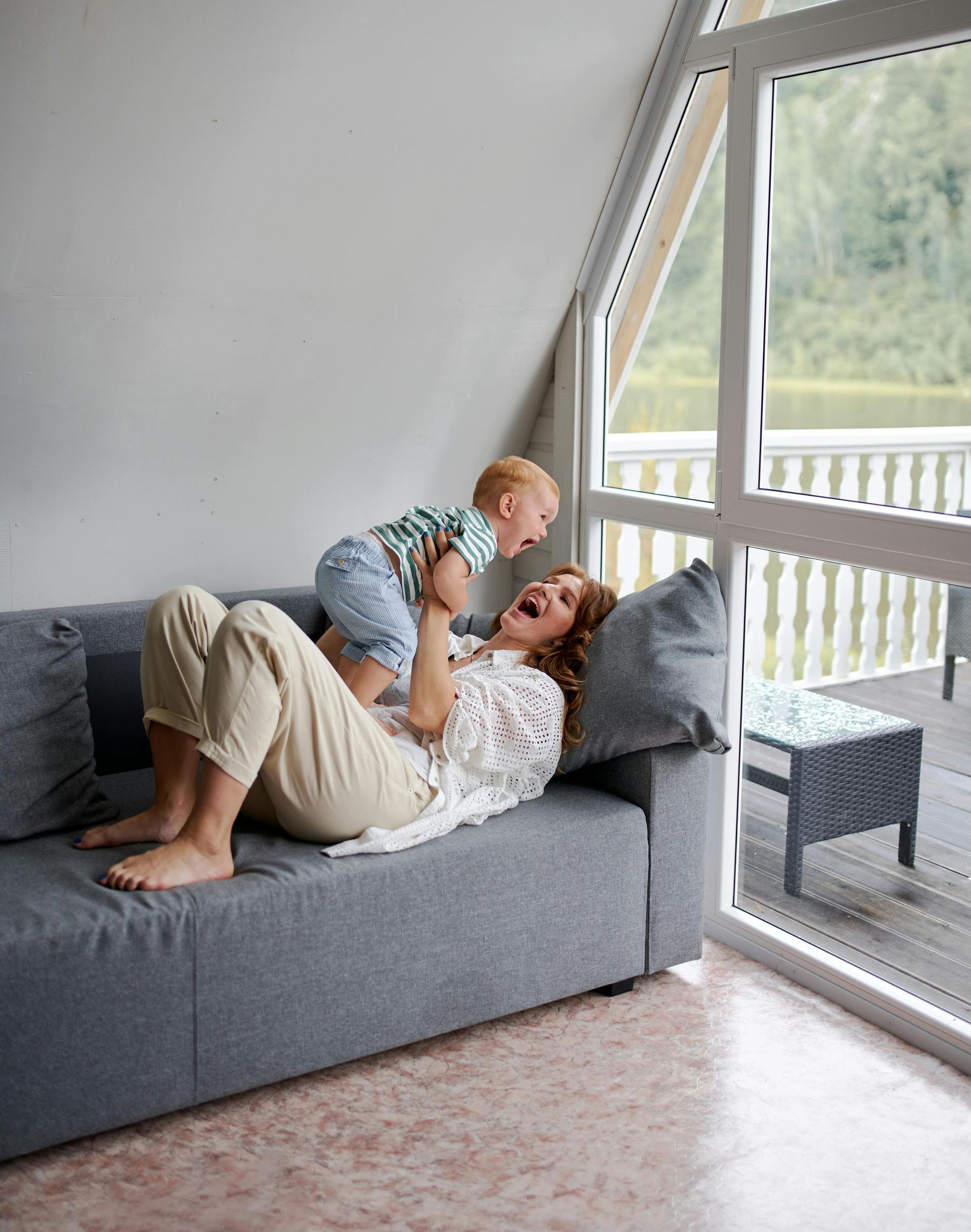 A woman is laying on a couch holding a baby in her arms.