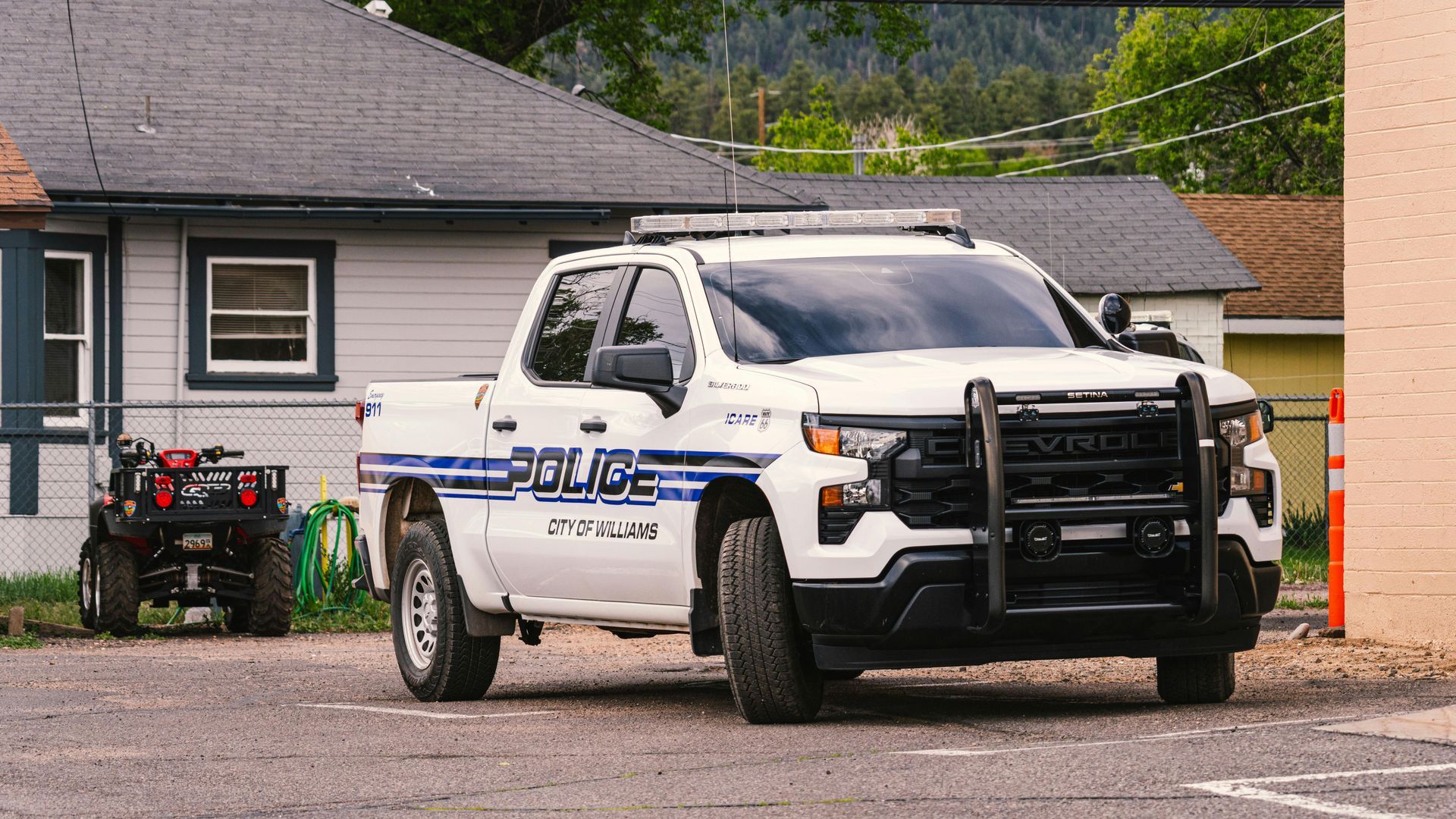 Police truck parked outside a building; an ATV is parked nearby.
