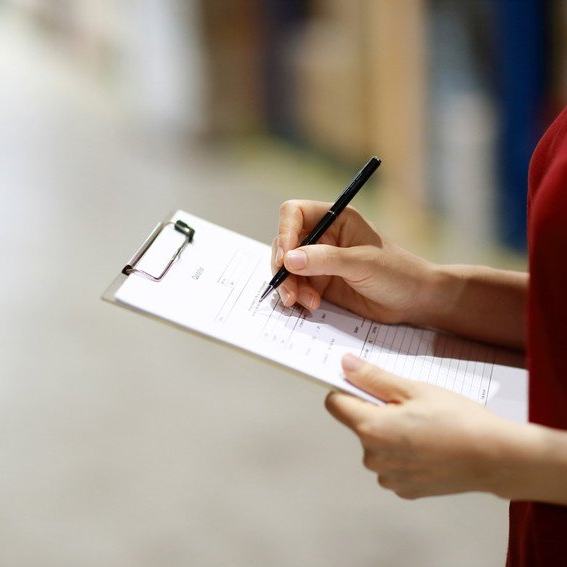 woman in red shirt writing on a clipboard