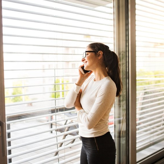 woman making a phone call next to a window