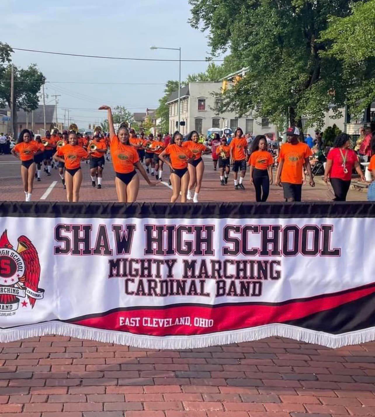 Shaw High School band marching in orange and black uniforms with banner in East Cleveland.