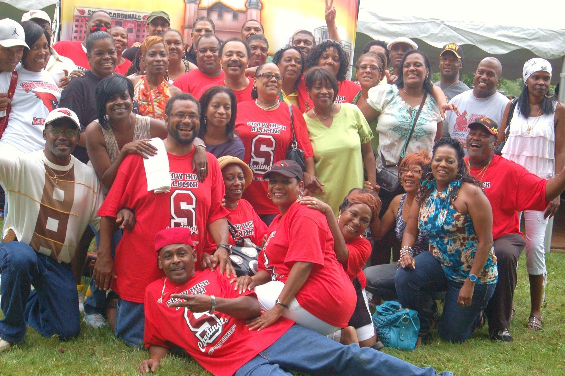 Large group of people in red shirts gathered outside; many smiling, some posing for a photo.