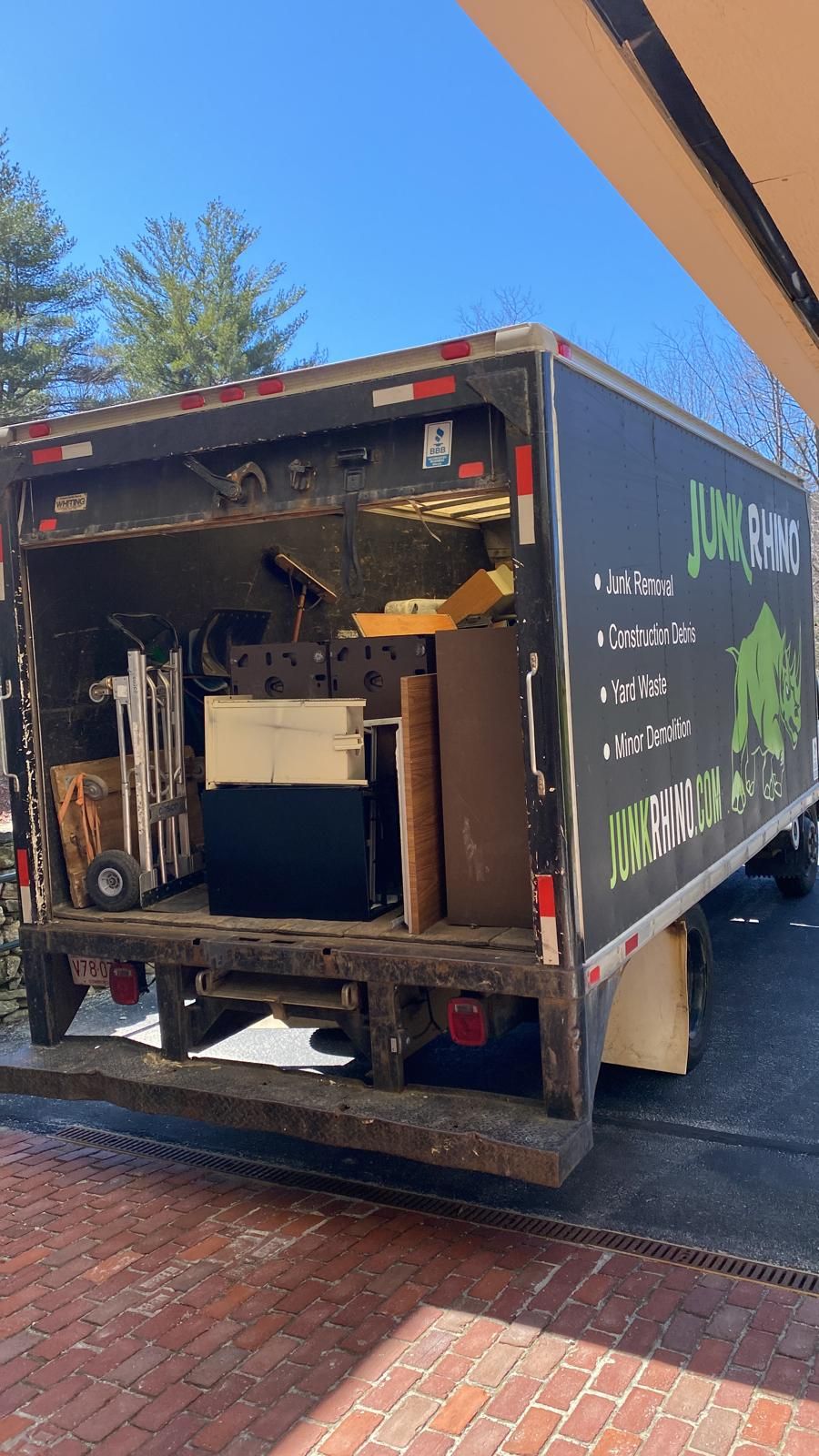 Open back of a moving truck loaded with furniture and household items on a sunny day.