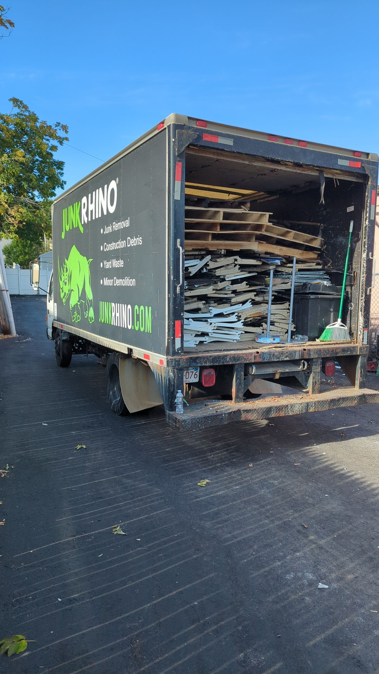A black box truck with the Rhino logo parked outside, loaded with wooden planks.