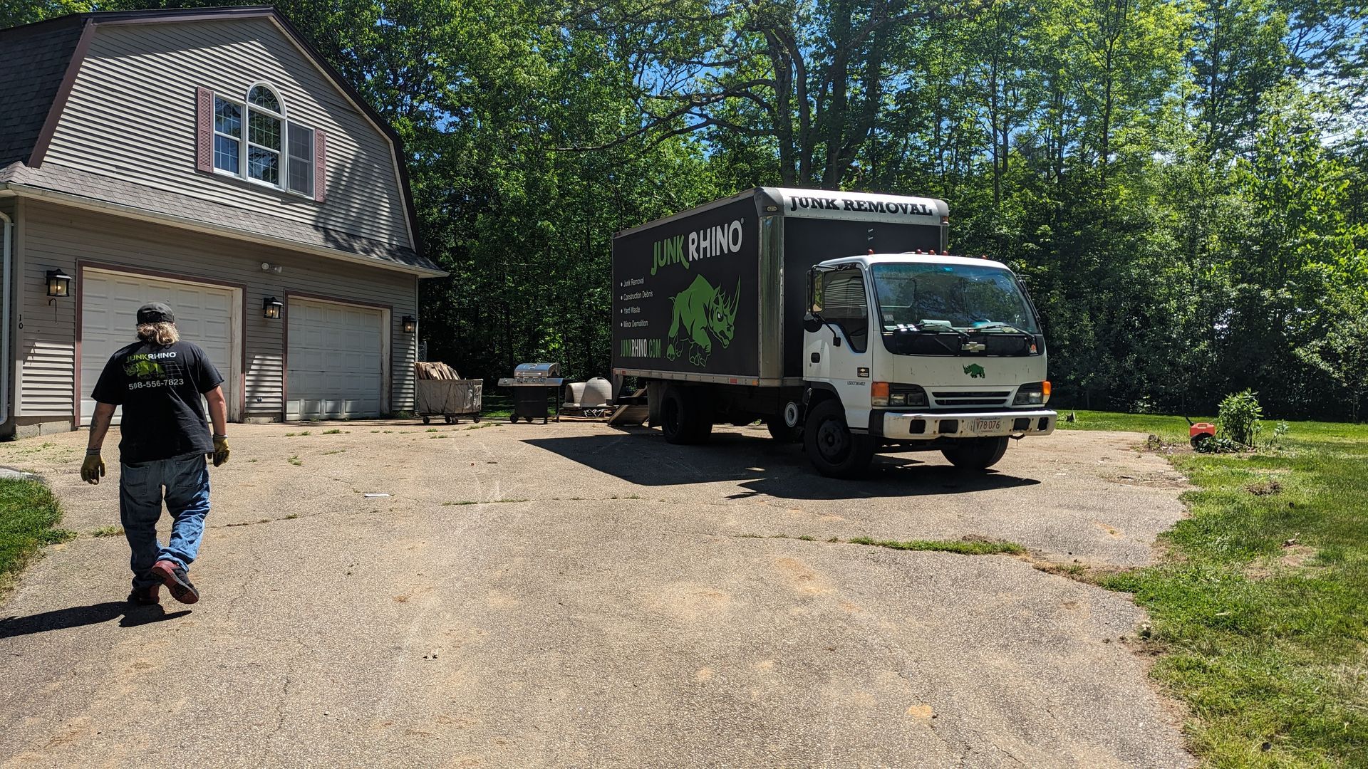 Man walking toward a moving truck parked in a driveway in front of a house.