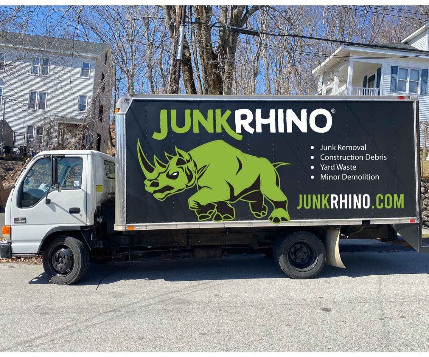 Junk Rhino truck parked on a street; a green rhinoceros logo on the side; website address visible.