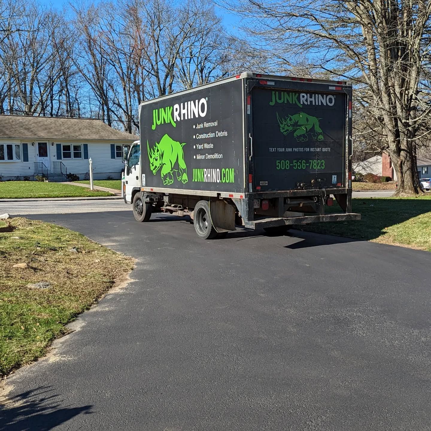 Junk Rhino truck parked on a driveway in front of a house on a sunny day.