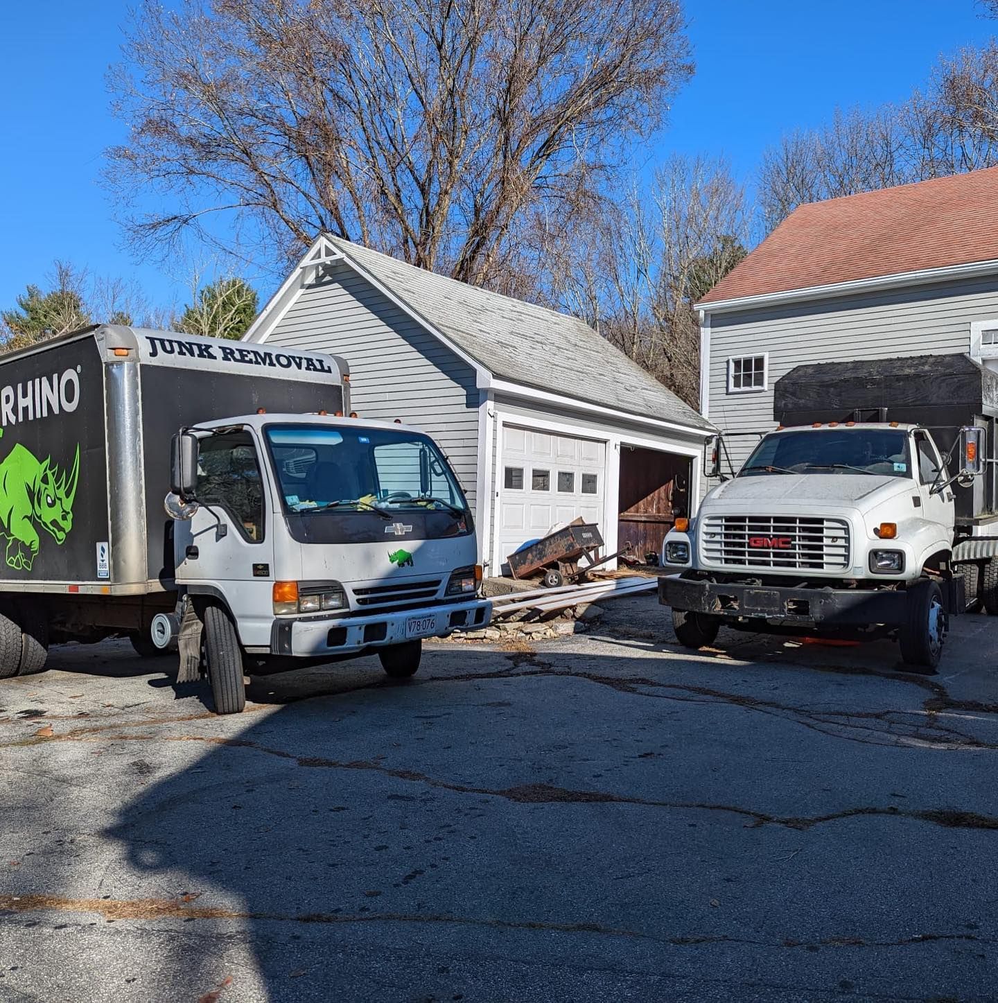 Three work trucks parked in front of a garage and a house on a sunny day.