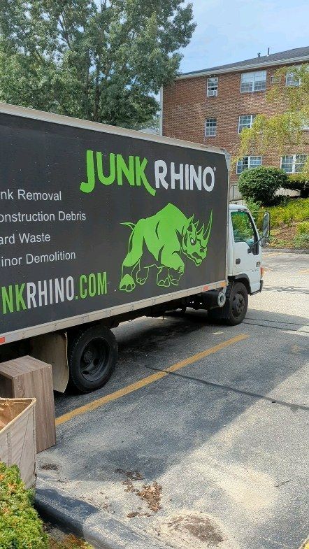 Junk Rhino truck parked in front of an apartment building. The truck has the company logo and text on its side.