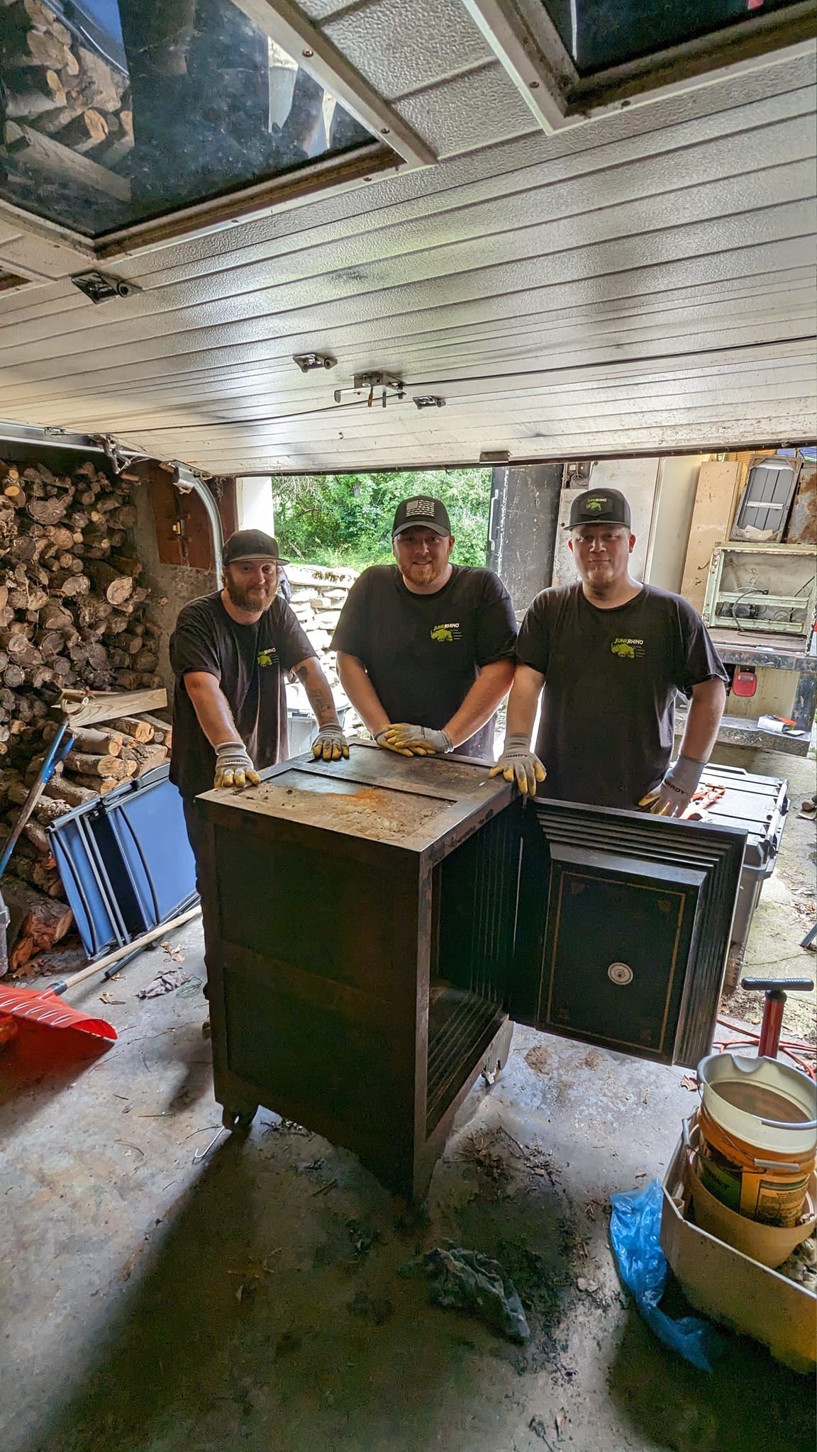 Three men in black shirts with hats, posing by a dark metal cabinet.