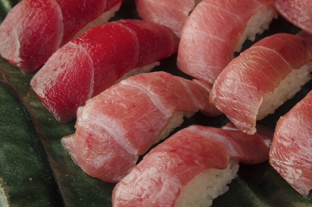 Nigiri de sushi con atún rojo en un plato verde.