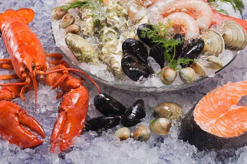 Plato de mariscos en hielo: langosta, salmón, ostras, mejillones, almejas y camarones.