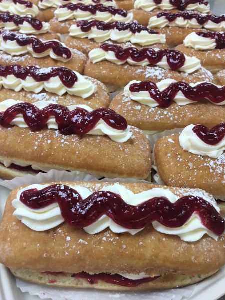 A bunch of donuts with jelly and whipped cream on them