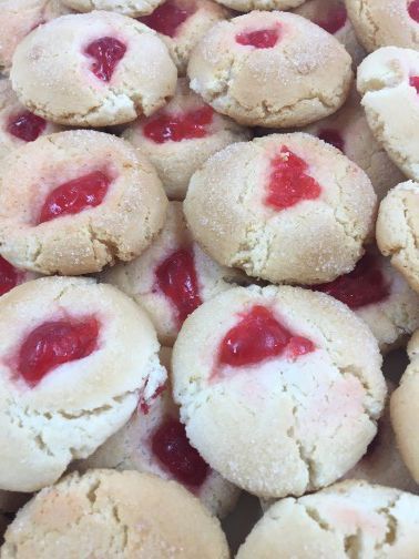 A pile of cookies with cherries in them on a table.