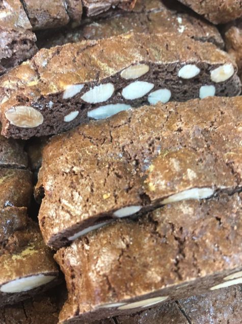 A close up of a pile of brownies with almonds on top.